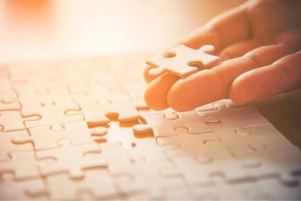 Hand setzt ein Puzzleteil in ein Puzzle ein, Symbol für Lösungsfindung und Begleitung durch Heilpraktiker Celle.
